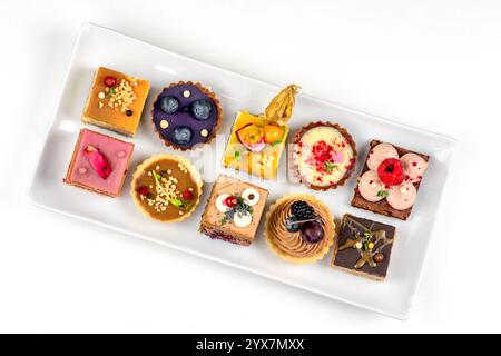 Many various cakes on plate on white background. Stock Photo