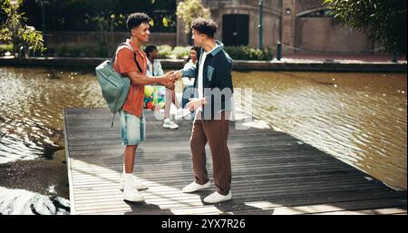 People, students and campus for shaking hands, outdoor and friends talking on education. Men, academy and support with university project or module Stock Photo
