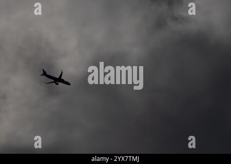 Airbus A321 jet passenger aircraft flying under dark clouds in the sky, England, United Kingdom, Europe Stock Photo