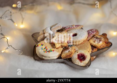 A plate with various Christmas biscuits on white, fairy lights in the background Stock Photo