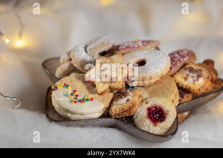 Various Christmas biscuits on a plate with fairy lights in the background Stock Photo