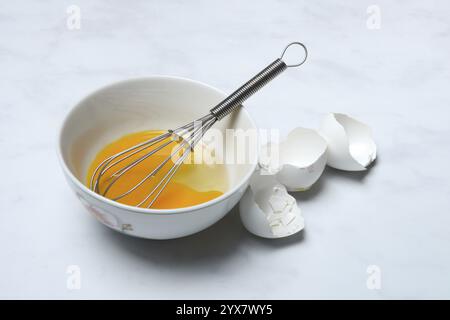 Whipped egg in shell with whisk, egg shells Stock Photo