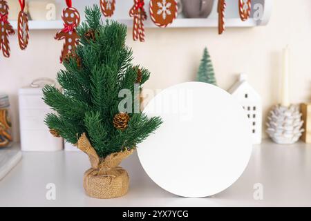 Small Christmas tree with pine cones and blank white circle, round paper shape for text. Holiday ornaments and decorations, cozy festive atmosphere fo Stock Photo