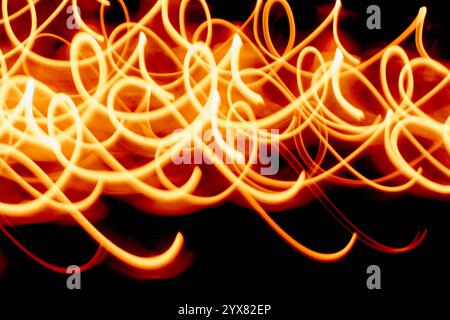 This image features dynamic light trails creating abstract patterns against a vibrant orange background, perfect for creative projects needing energet Stock Photo