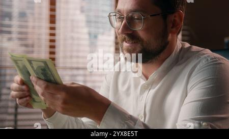 Joyful Caucasian businessman guy trader executive boss counting money savings banknotes in office worker smile accountant male calculate company Stock Photo