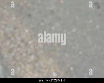 blurred river sand bank with brown and grey small pebbles as empty kopi space, grainy light natural texture in blur, bokeh of rocky shore Stock Photo