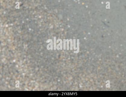 blurred light brownish background of fine textured river or sea wet sand, bokeh with empty copy space with grainy out of focus backdrop Stock Photo