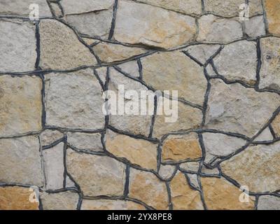 abstraction from facing stone of brown shades with black joints, decoration of exterior of wall or fence using solid natural stone, graphic resource Stock Photo