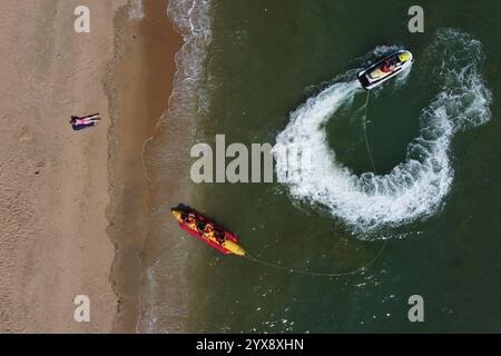 Pattaya, Thailand - May 18, 2023: Woman, wearing a pink swimsuit, sunbath as a man rides a jet ski in Jomtien beach, a resort region near Bangkok. Stock Photo