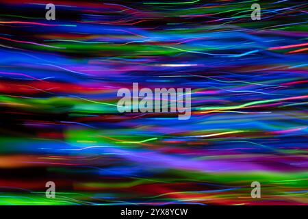 Abstract multi-layered effect created by LED lights photographed outdoors at night giving appearance of chaotic wavy lines moving in ocean of colour. Stock Photo