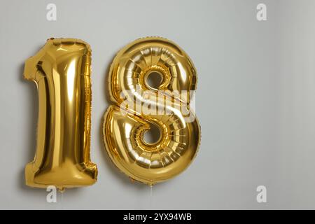 Coming of age party - 18th birthday. Number shaped balloons on light grey background, space for text Stock Photo