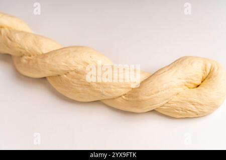 The dough is braided into a pigtail on a white background. The process of preparing baked goods. High quality photo Stock Photo