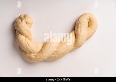 The dough is braided into a pigtail on a white background. The process of preparing baked goods. High quality photo Stock Photo