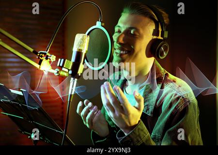 Vocalist with headphones singing into microphone in professional record studio. Sound waves Stock Photo