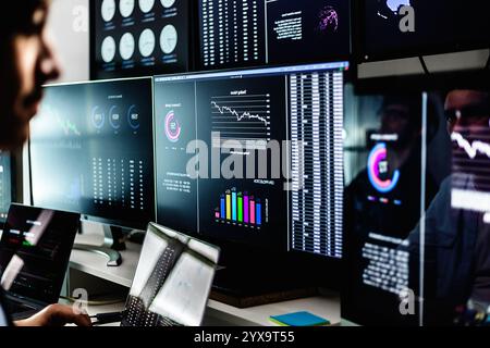 Stock traders working with financial data on multiple computer screens Stock Photo