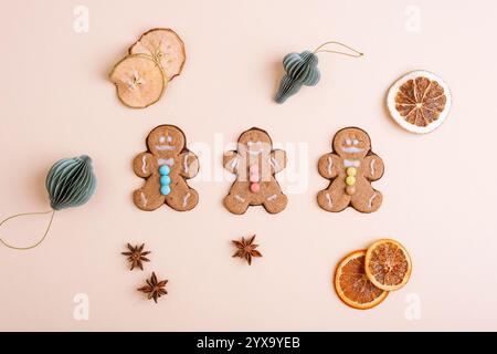 Gingerbread cookies arranged with dried orange slices, star anise, and holiday ornaments on a beige background. Top view, flat lay. Stock Photo
