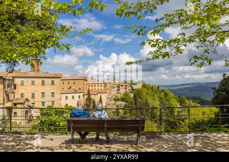 Senior couple on a bench enjoying the view over historic city Volterra, Italy Stock Photo