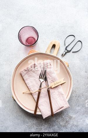Overhead view of a simple pink place setting with an autumn tag on a table in sunlight Stock Photo