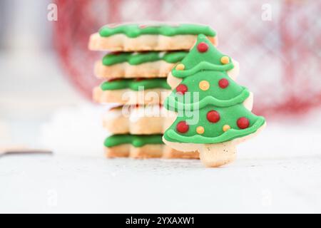 Close-up of a Christmas tree cookie with icing leaning against a stack of cookies on a table Stock Photo