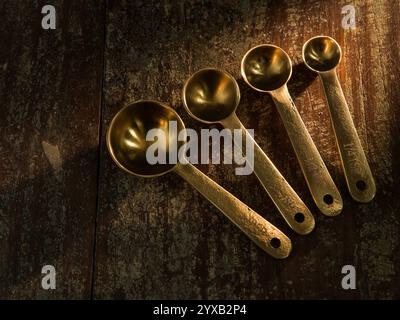 Golden Measuring Spoons on distressed wooden backdrop dramatic lighting Stock Photo