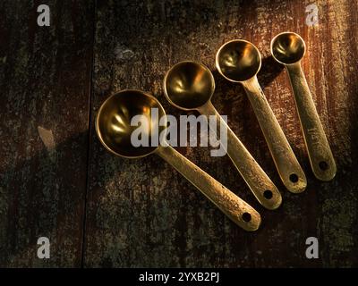 Golden Measuring Spoons on distressed wooden backdrop dramatic lighting Stock Photo