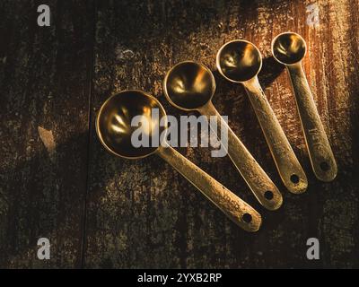 Golden Measuring Spoons on distressed wooden backdrop dramatic lighting Stock Photo