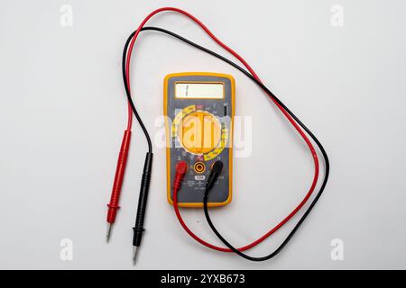 Yellow and gray digital multimeter with probes showing one on display, resting on white background Stock Photo