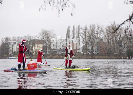 Water sports enthusiasts dressed as Santas ride SUPs on the Spree in Berlin on 14 December 2024 Stock Photo