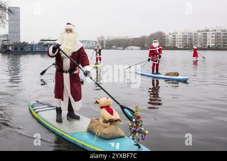 Water sports enthusiasts dressed as Santas ride SUPs on the Spree in Berlin on 14 December 2024 Stock Photo