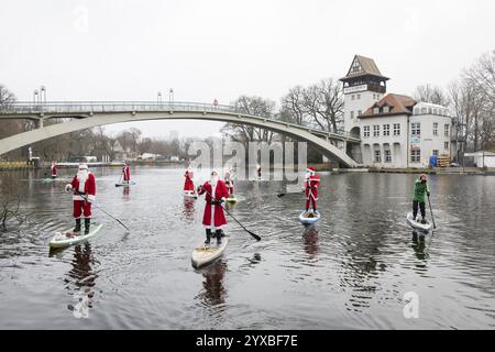 Water sports enthusiasts dressed as Santas ride SUPs on the Spree in front of the Insel der Jugend in Berlin on 14 December 2024 Stock Photo