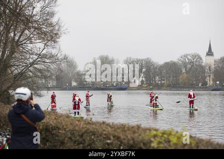 Water sports enthusiasts dressed as Santas ride SUPs on the Spree through Alt-Stralau in Berlin on 14 December 2024 Stock Photo