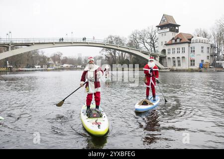 Water sports enthusiasts dressed as Santas ride SUPs on the Spree in front of the Insel der Jugend in Berlin on 14 December 2024 Stock Photo