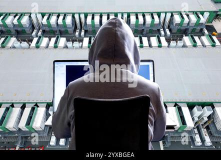 Close-up of a hacker behind a laptop and a large datacenter in the background Stock Photo