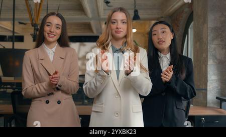Smiling satisfied congratulation business multiethnic diversity women three multiracial females businesswomen Korean Asian Caucasian girls in office Stock Photo