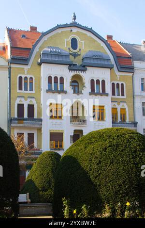 Charming Art Nouveau buildings in Timisoara, Romania, with colorful facades, decorative details, and lush greenery under a bright blue sky. Stock Photo