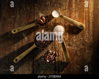 Golden Measuring Spoons with Ingredients Chocolate Cocoa Sugar Milk on distressed wooden backdrop dramatic lighting Stock Photo