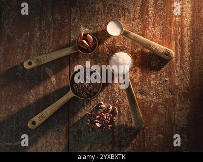 Golden Measuring Spoons with Ingredients Chocolate Cocoa Sugar Milk on distressed wooden backdrop dramatic lighting Stock Photo