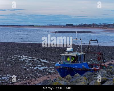 A Crewman salvaging the electronic equipment from a small Fishing Boat that washed up onto Arbroath West Links after a storm. Stock Photo