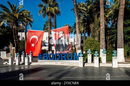 A monument to female scientific achievement, beside the Flag of Turkey and a large sign for Bodrum. Turkiye Stock Photo