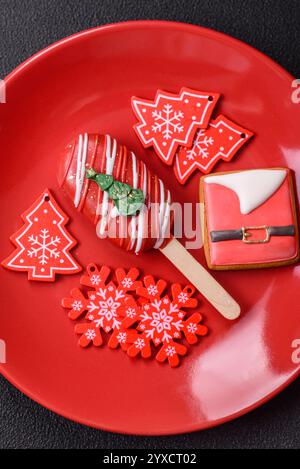 Natural popsicle ice cream on a stick covered with chocolate in the style and colors of Christmas and New Year on a dark concrete background Stock Photo