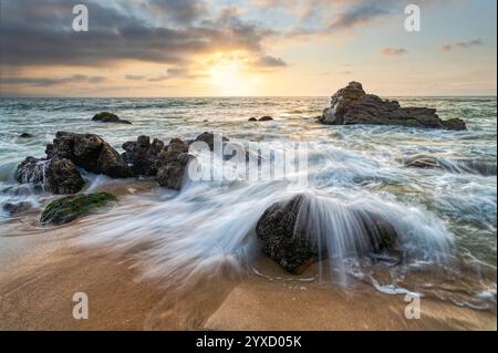 Water Is Flowing Over Coastal Sea Rocks With A Colorful Sunset Sky Background Stock Photo
