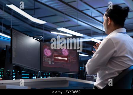 System administrator in server hub trying to protect hardware from hacker attack stealing sensitive information. Data center cybersecurity specialist fighting virus during security breach Stock Photo