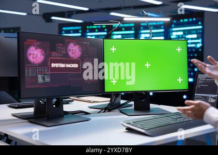 Admin in server hub establishment frightened by hacker passing firewall and stealing data. Security breach notification on green screen monitor in data center making IT expert panic Stock Photo