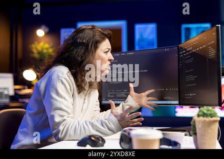 Programmer with frown on face trying to fix vulnerabilities in software enabling attackers to compromise systems. Cybersecurity expert focused on patching security exposures, panicking Stock Photo