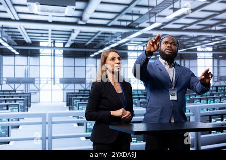 Coworkers using AR in data center, ensuring cybersecurity and efficient network management. Engineers in server hub optimizing data center equipment with augmented reality technology Stock Photo