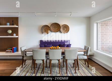 Straight-on view of dining area of open apartment space with built-in bench that extends to shelving Stock Photo