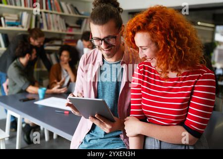 Friendly happy multiethnic coworker male and female having fun with tablet, working together Stock Photo