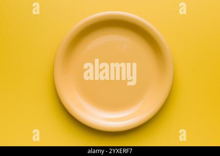 Empty yellow plate on an yellow background. Top view. Stock Photo