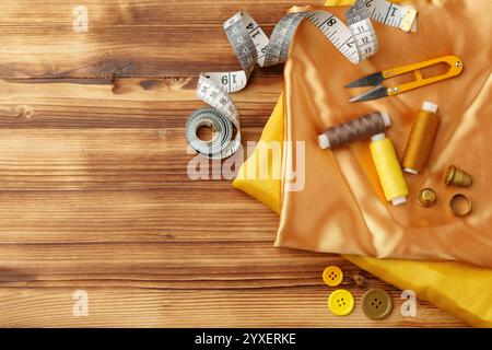 Crafting essentials arranged on golden satin fabric with sewing tools and colorful buttons scattered around Stock Photo