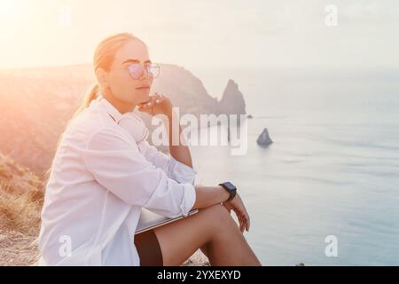 Woman Sunset Cliffs Ocean - A woman sits on a cliff overlooking the ocean at sunset. Stock Photo